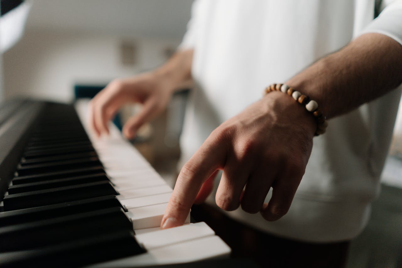 A detailed close-up of hands playing a keyboard piano indoors, emphasizing musical expression.