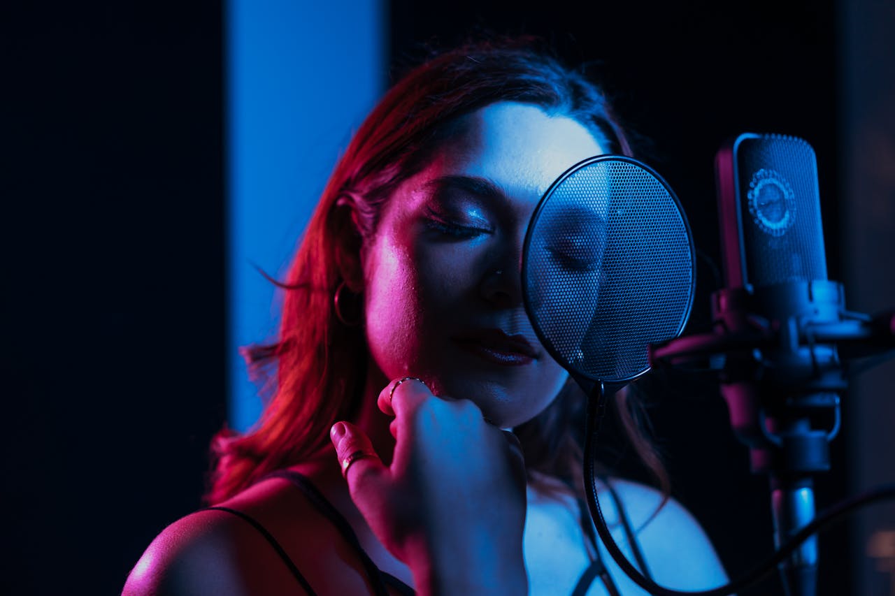 A captivating portrait of a female singer with closed eyes performing in a dimly lit recording studio.