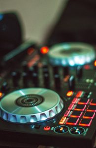 Close-up photo of a DJ controller with illuminated buttons, mixing dials, and controls.