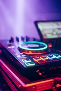 Dynamic DJ setup featuring illuminated neon sound mixer in a vibrant nightclub setting.