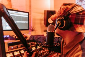 A man wearing headphones records audio in a professional studio with a microphone.