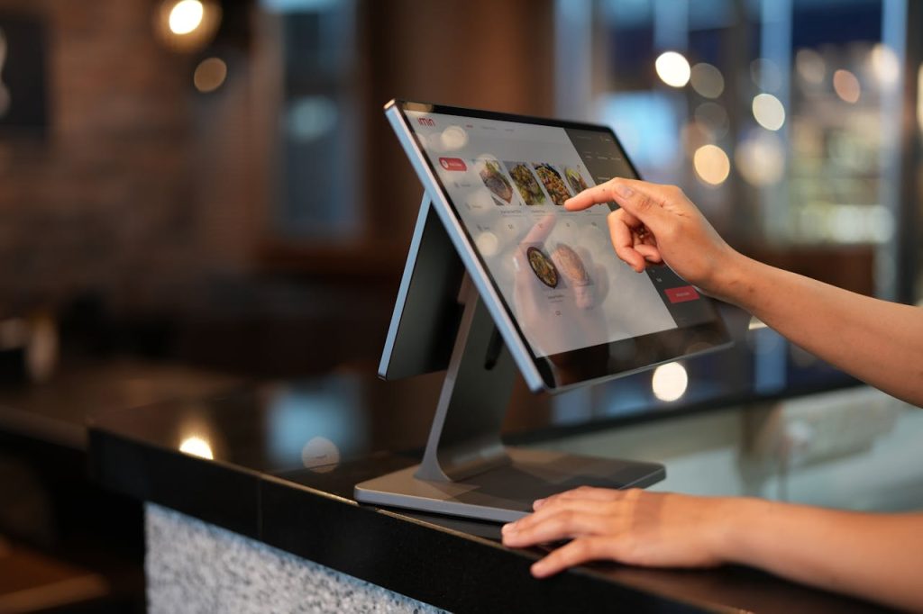 a-close-up-shot-of-a-cashier-using-a-point-of-sale-system-12935074 Close-up of a hand interacting with a touchscreen POS system in a restaurant setting.